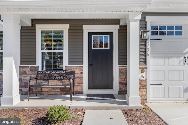 doorway to property with covered porch and a garage