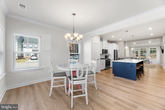 dining area featuring light hardwood / wood-style floors, crown molding, a chandelier, and sink