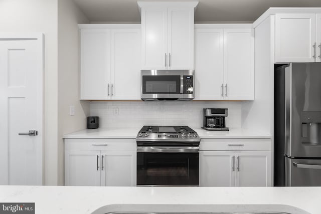 kitchen with appliances with stainless steel finishes, white cabinetry, and tasteful backsplash