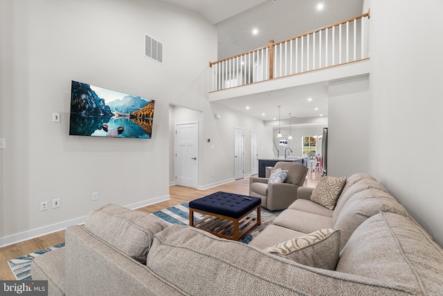 living room with sink, light hardwood / wood-style flooring, and high vaulted ceiling