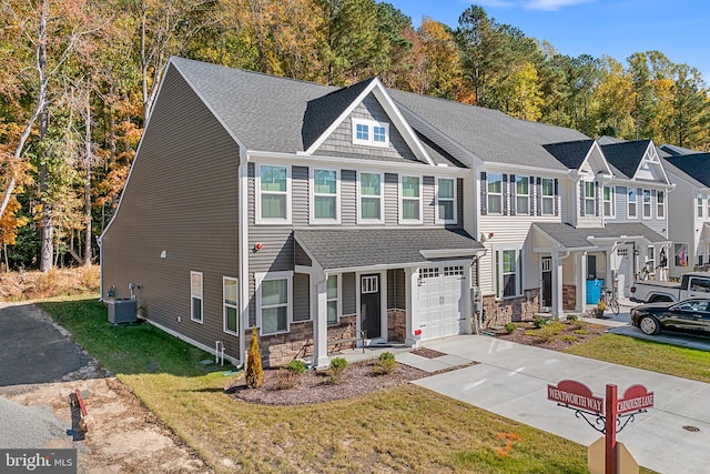 view of front of home featuring a front lawn, central AC unit, and a garage