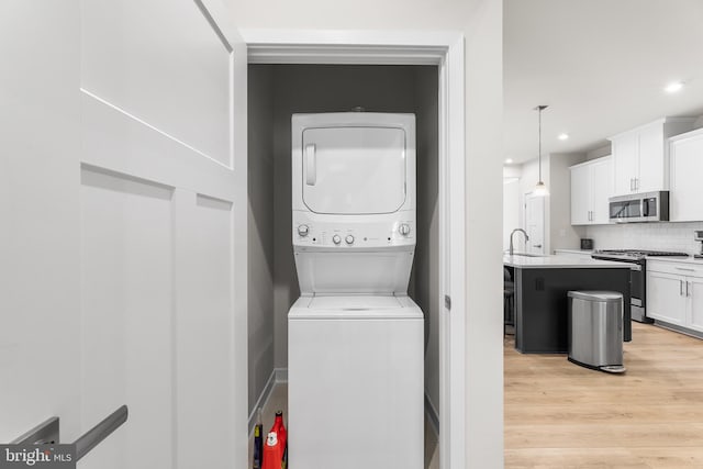 laundry room with light hardwood / wood-style floors, sink, and stacked washer and clothes dryer