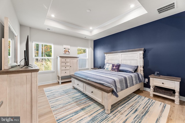 bedroom featuring light hardwood / wood-style floors and a raised ceiling