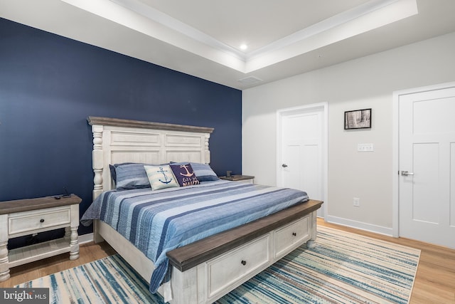 bedroom with hardwood / wood-style floors and a raised ceiling