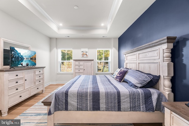 bedroom with a raised ceiling and light wood-type flooring