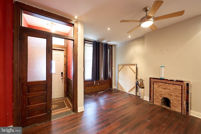 entrance foyer with a brick fireplace, dark hardwood / wood-style floors, and ceiling fan