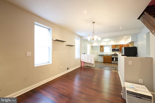 kitchen featuring a chandelier, stainless steel appliances, dark wood-type flooring, and hanging light fixtures