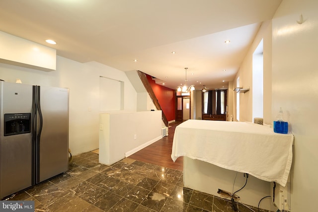 kitchen with stainless steel fridge, a notable chandelier, pendant lighting, and dark hardwood / wood-style flooring