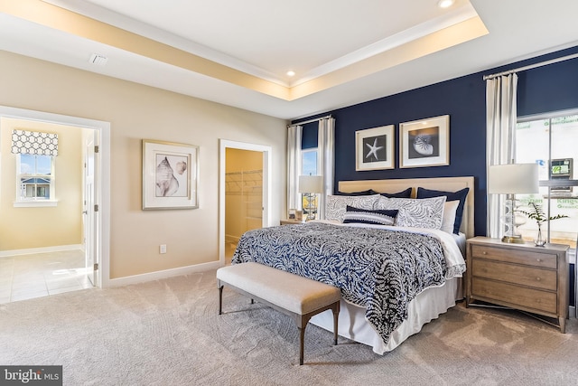 carpeted bedroom featuring a closet, a tray ceiling, and a walk in closet