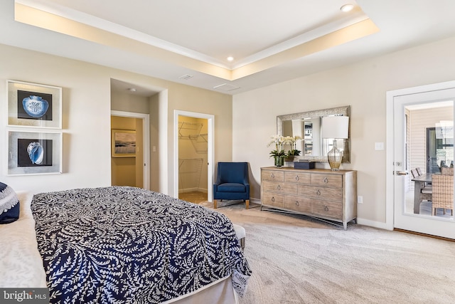 bedroom with a spacious closet, a closet, a tray ceiling, and light colored carpet