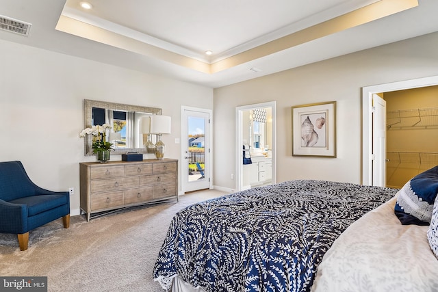 carpeted bedroom with a closet, ensuite bathroom, a tray ceiling, and a walk in closet