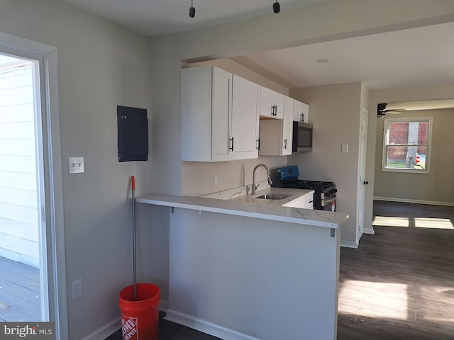 kitchen featuring sink, dark hardwood / wood-style flooring, kitchen peninsula, white cabinetry, and stainless steel appliances