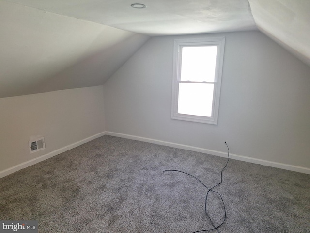 additional living space featuring vaulted ceiling and carpet flooring