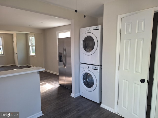 clothes washing area featuring stacked washer and dryer and dark hardwood / wood-style flooring