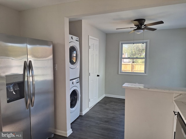 clothes washing area featuring dark wood-type flooring, ceiling fan, and stacked washer and clothes dryer