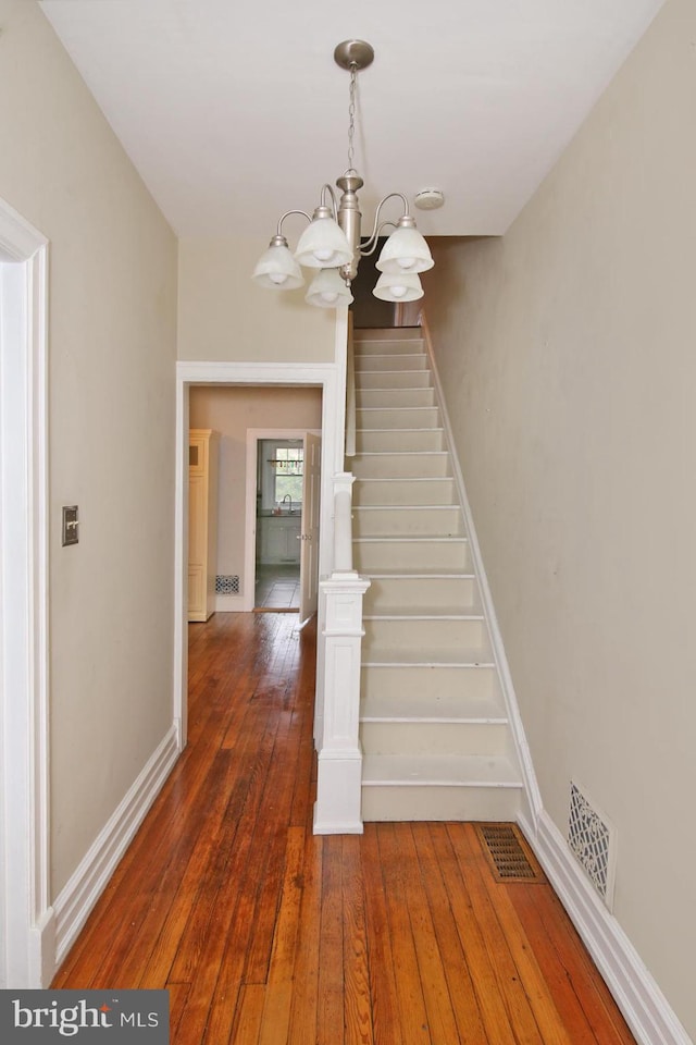 stairway with a chandelier and wood-type flooring