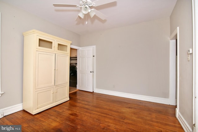 unfurnished bedroom featuring washer / clothes dryer, ceiling fan, and dark wood-type flooring