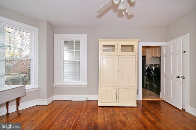 unfurnished bedroom featuring independent washer and dryer, dark hardwood / wood-style floors, and multiple windows