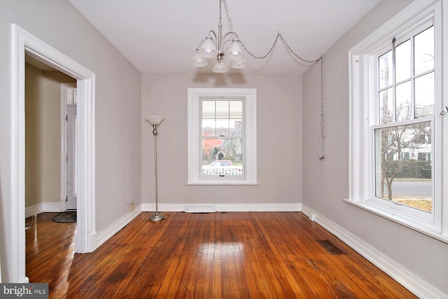 unfurnished dining area with hardwood / wood-style flooring and a notable chandelier