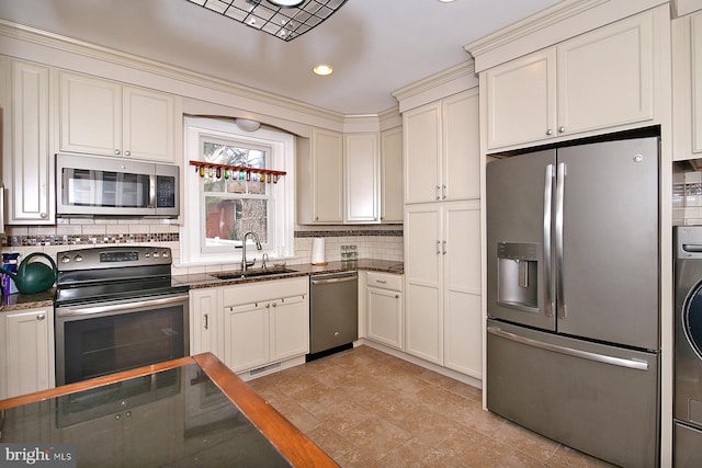 kitchen featuring white cabinetry, sink, stainless steel appliances, backsplash, and dark stone counters