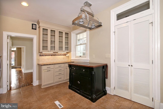 kitchen with decorative backsplash, light hardwood / wood-style flooring, and dark stone countertops