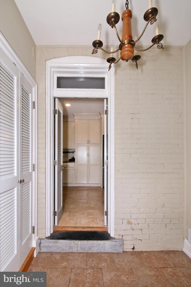 hallway with a chandelier and brick wall