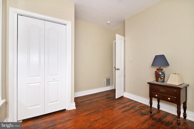 unfurnished bedroom with dark hardwood / wood-style floors and a closet