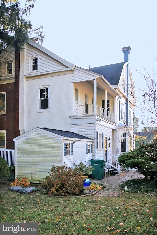 rear view of house featuring a balcony and a yard