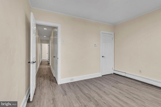 unfurnished room with baseboard heating, crown molding, and light wood-type flooring