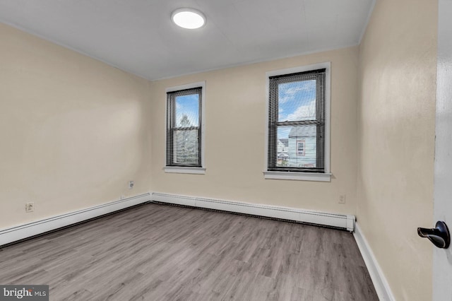 empty room featuring baseboard heating and light hardwood / wood-style flooring