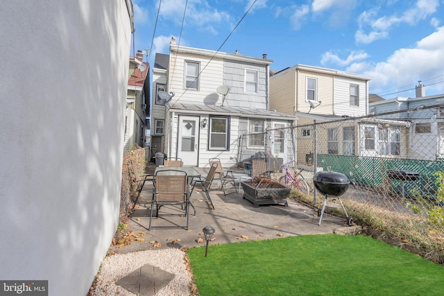 back of property with a yard, a patio, and an outdoor fire pit