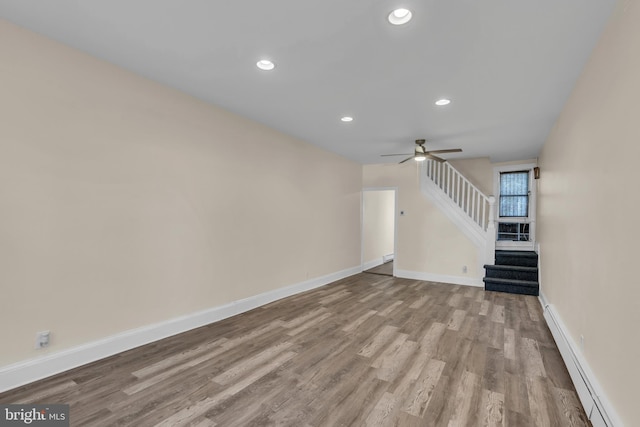 unfurnished living room featuring ceiling fan, light hardwood / wood-style floors, and a baseboard heating unit