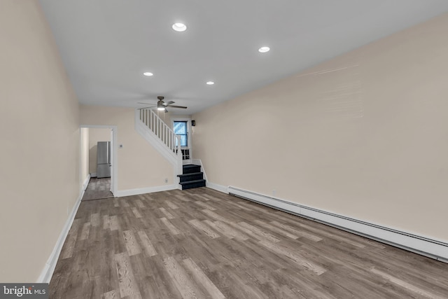 unfurnished living room featuring ceiling fan, light hardwood / wood-style flooring, and a baseboard heating unit