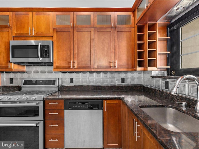kitchen with brown cabinetry, backsplash, stainless steel appliances, and a sink