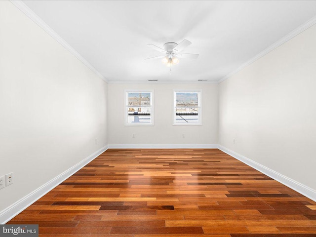 empty room with crown molding, wood finished floors, baseboards, and a ceiling fan