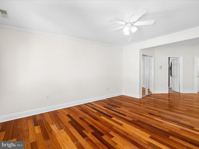 spare room with a ceiling fan, baseboards, ornamental molding, visible vents, and wood finished floors
