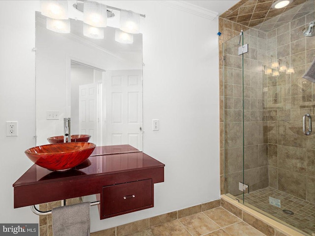 full bath with a stall shower, baseboards, a sink, tile patterned floors, and crown molding