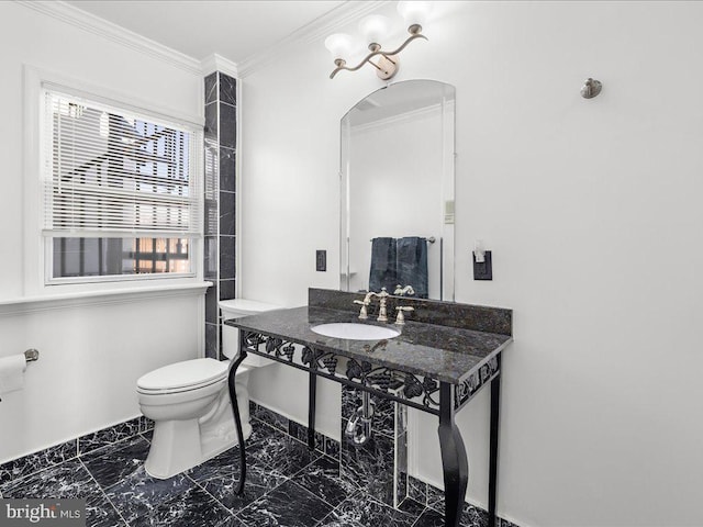 bathroom featuring toilet, marble finish floor, ornamental molding, and a sink