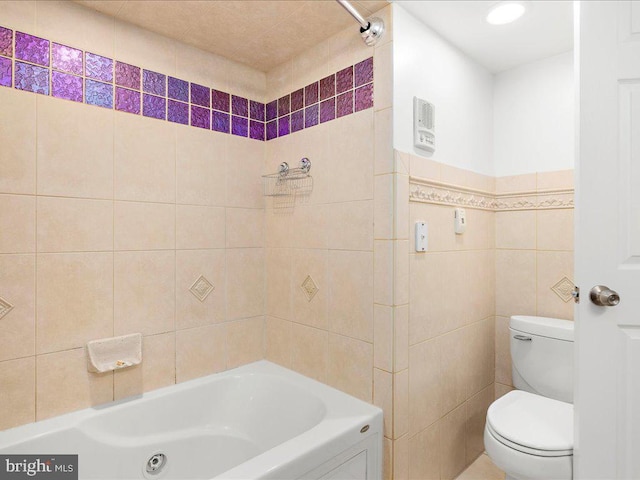 bathroom with tub / shower combination, tile walls, and toilet