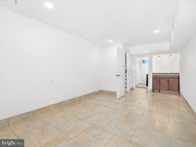 spare room with baseboards, bar area, recessed lighting, and a sink