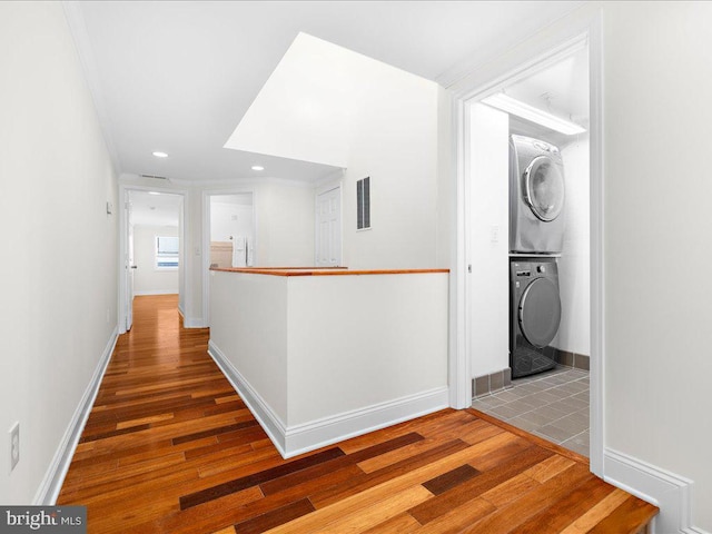 hall with wood-type flooring and stacked washing maching and dryer