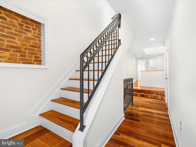 stairs featuring a skylight, hardwood / wood-style floors, and recessed lighting
