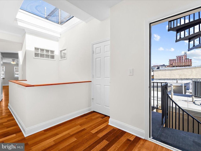 interior space featuring baseboards, an upstairs landing, crown molding, and wood finished floors