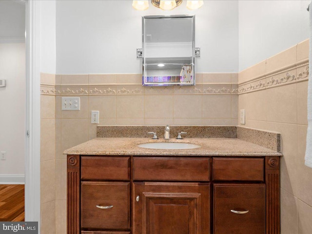 bathroom featuring wood-type flooring, vanity, tile walls, and ornamental molding