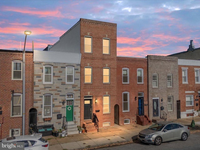 view of property featuring entry steps, brick siding, and stone siding