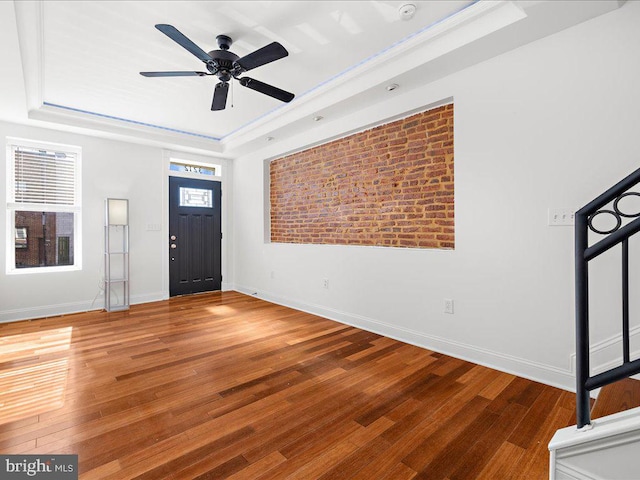 foyer featuring a raised ceiling, ceiling fan, and wood-type flooring