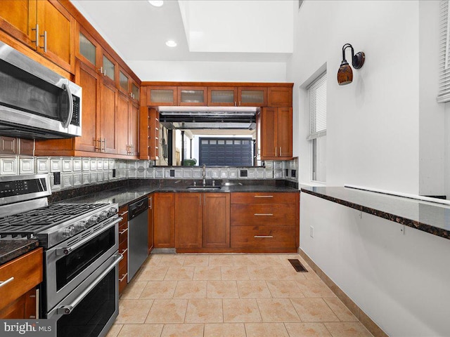 kitchen with decorative backsplash, appliances with stainless steel finishes, a wealth of natural light, and dark stone countertops