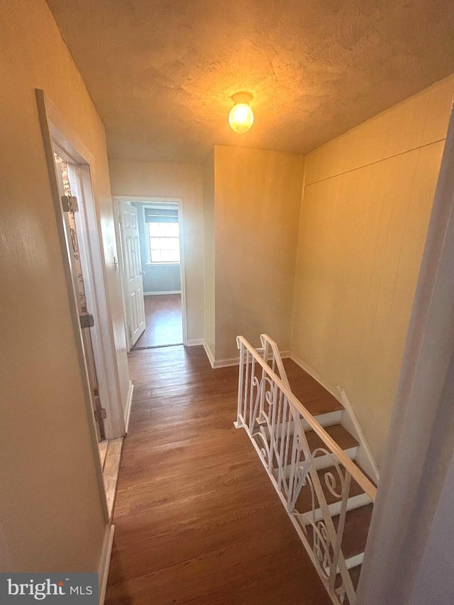 hallway with hardwood / wood-style floors and a textured ceiling