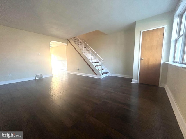 unfurnished living room featuring dark hardwood / wood-style flooring and a healthy amount of sunlight