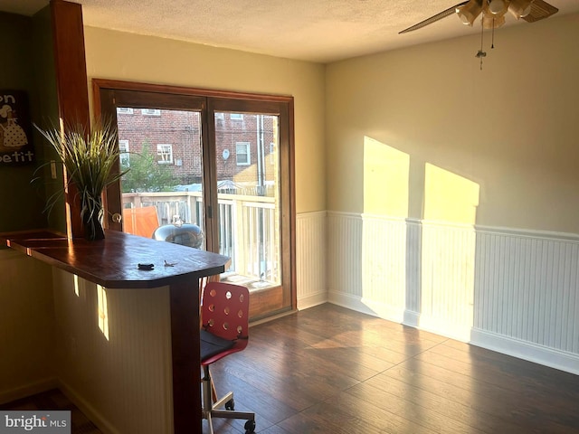 unfurnished dining area featuring ceiling fan, dark hardwood / wood-style flooring, and a textured ceiling